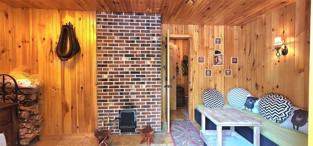living area featuring wood ceiling, a wood stove, and wooden walls