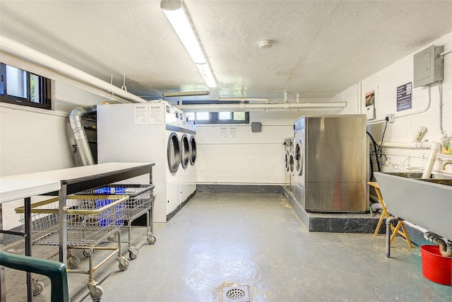 basement with washing machine and clothes dryer, a textured ceiling, and electric panel