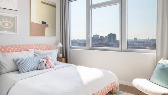 bedroom with baseboards, wood finished floors, and a city view