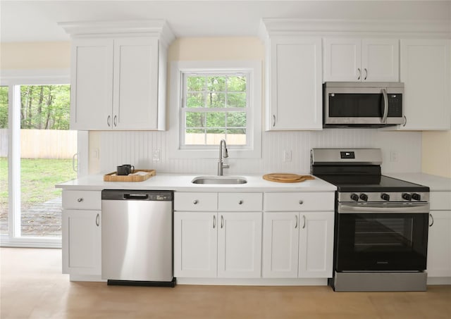 kitchen with appliances with stainless steel finishes, a sink, white cabinetry, and light countertops
