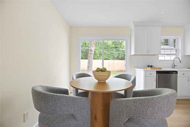dining area with healthy amount of natural light, light wood-type flooring, and bar