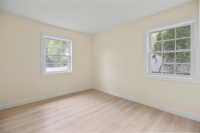 spare room featuring healthy amount of natural light, baseboards, and light wood-style floors