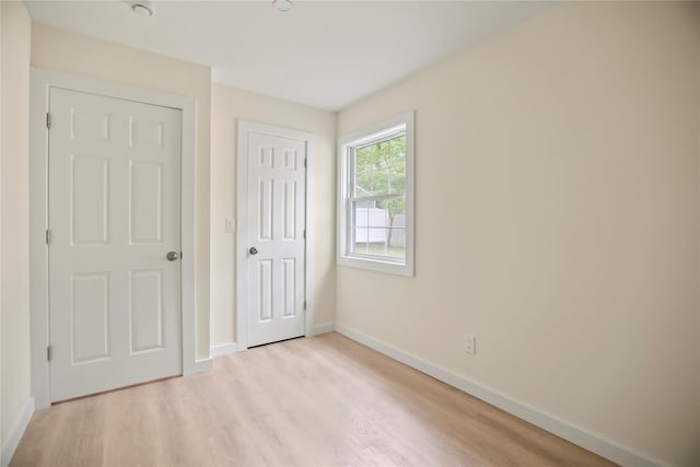 unfurnished bedroom featuring light wood finished floors, baseboards, and a closet