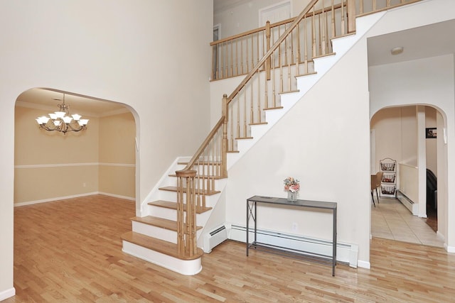 67 N Airmont Rd, Suffern, NY 10901 - staircase with a baseboard radiator, arched walkways, wood finished floors, a high ceiling, and crown molding