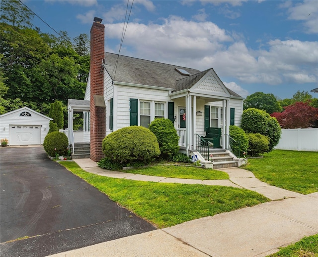 964 Pemart Ave, Peekskill, NY 10566 - view of front of property with an outdoor structure, a chimney, a detached garage, asphalt driveway, and a porch