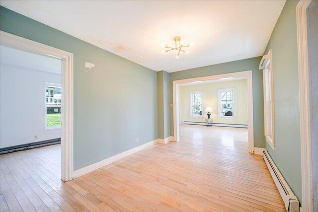 239-241 Hurleyville Main St, Hurleyville, NY 12747 - corridor featuring a baseboard heating unit, baseboard heating, a chandelier, light wood finished floors, and baseboards