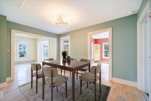 239-241 Hurleyville Main St, Hurleyville, NY 12747 - dining space with a baseboard heating unit, light wood-type flooring, baseboards, and a chandelier