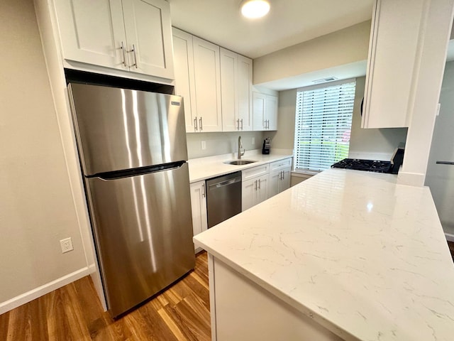 17 Cheyenne Ct Unit C17, Coram, NY 11727 - kitchen with appliances with stainless steel finishes, a sink, wood finished floors, white cabinetry, and light stone counters
