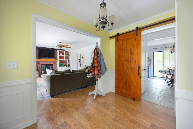 136 Foggintown Rd, Brewster, NY 10509 - living area featuring wainscoting, a barn door, a brick fireplace, built in features, and light wood-style flooring