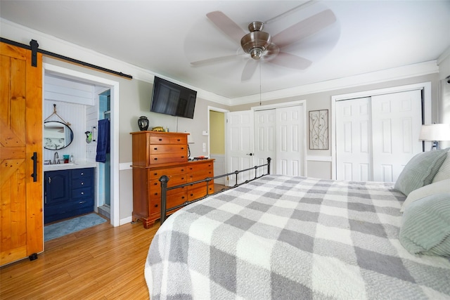 136 Foggintown Rd, Brewster, NY 10509 - bedroom featuring two closets, light wood-style floors, a barn door, ensuite bathroom, and ceiling fan