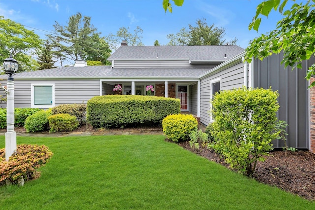 view of front of home with a front lawn, board and batten siding, a chimney, and a shingled roof