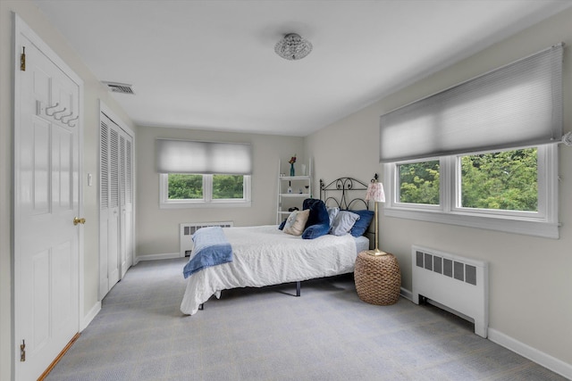 carpeted bedroom with radiator heating unit, multiple windows, and baseboards