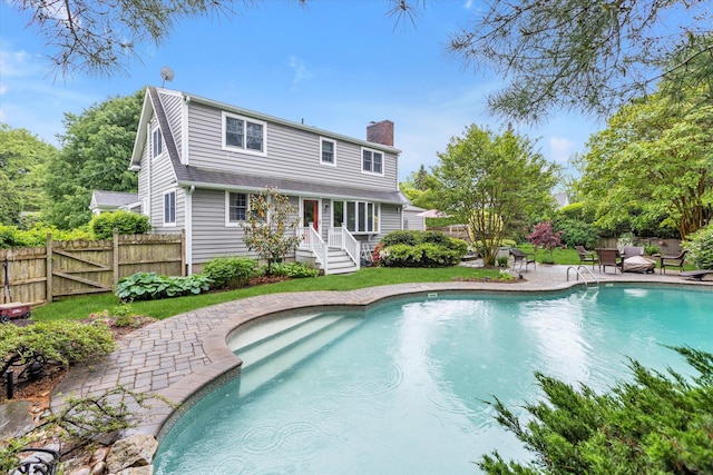 rear view of property with a chimney, a patio, and fence