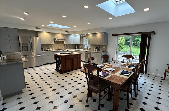 dining room with a skylight, light floors, and recessed lighting
