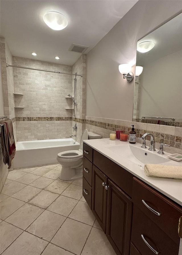 bathroom featuring tile patterned floors, shower / bathtub combination, toilet, vanity, and tile walls