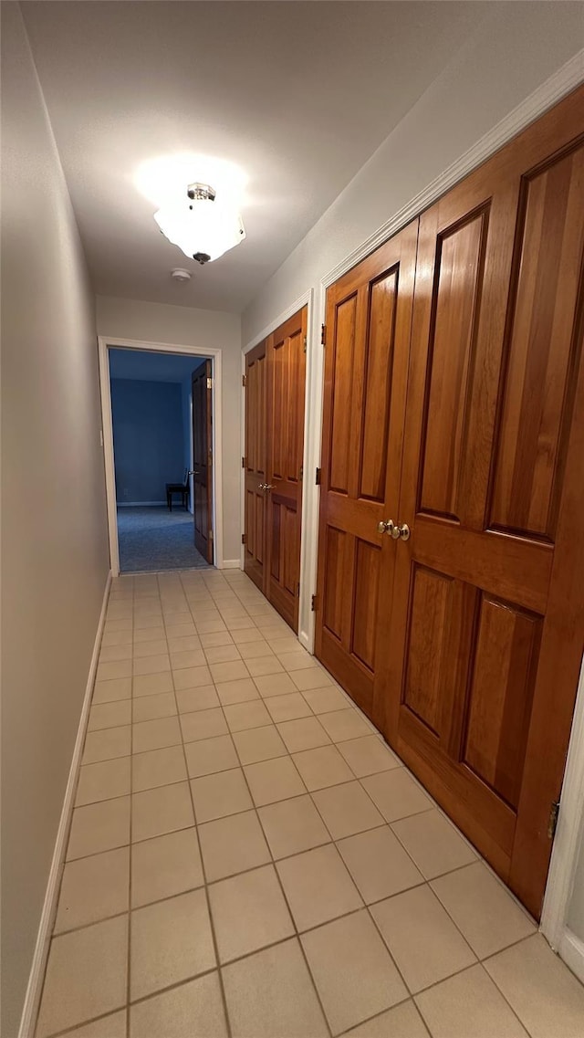 hallway with baseboards and light tile patterned flooring