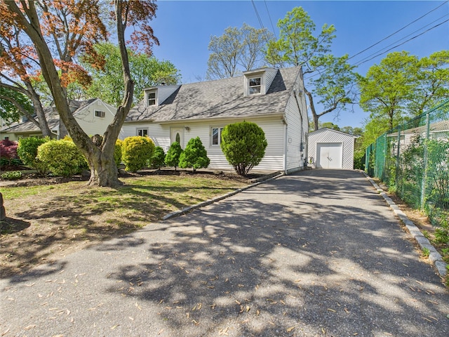 95 State Ave, Wyandanch, NY 11798 - view of front of property featuring asphalt driveway, fence, a garage, roof with shingles, and an outbuilding