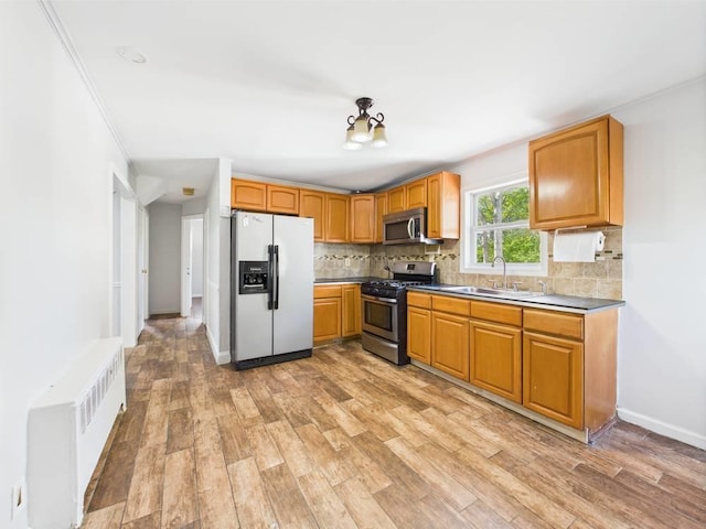 95 State Ave, Wyandanch, NY 11798 - kitchen with appliances with stainless steel finishes, a sink, tasteful backsplash, light wood-style flooring, and radiator