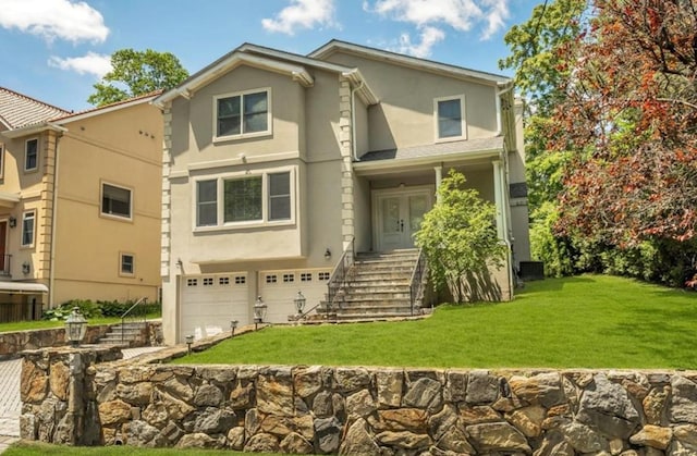 view of front of property with stucco siding, an attached garage, and a front yard