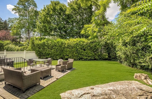 view of yard with outdoor lounge area, a patio, and view of wooded area