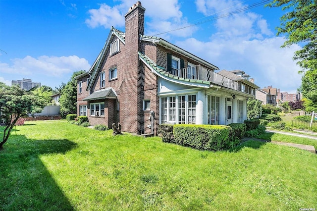 view of home's exterior featuring a balcony, a chimney, and brick siding