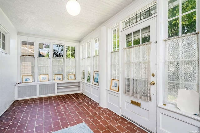 unfurnished sunroom with french doors, brick patterned floors, and a textured ceiling