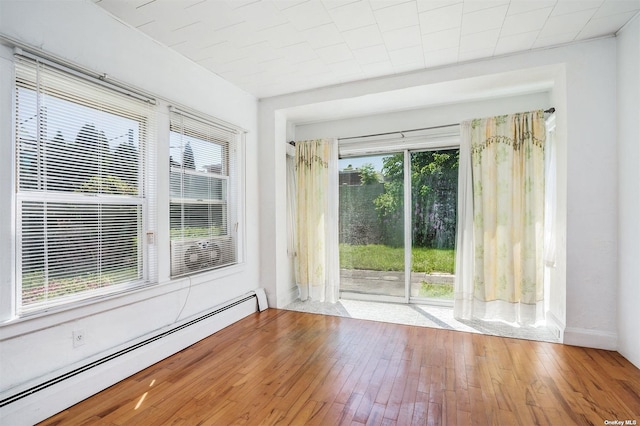 doorway to outside with baseboard heating, wood-type flooring, and baseboards