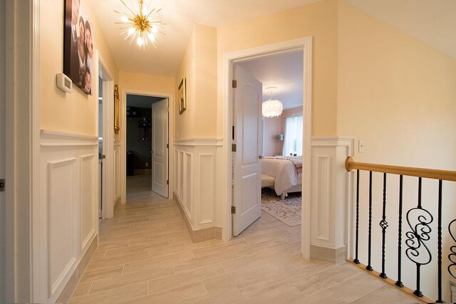 16 Kukas Rd, Monticello, NY 12701 - corridor featuring a chandelier, a decorative wall, wainscoting, and light wood-type flooring