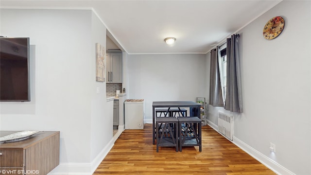 dining area featuring radiator, light wood-style floors, baseboards, and crown molding