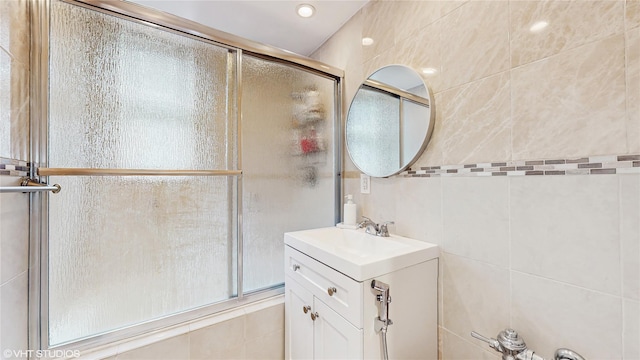 bathroom with tiled shower, tile walls, and vanity