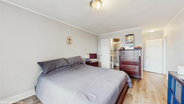 bedroom with light wood-style floors, crown molding, ensuite bath, and baseboards