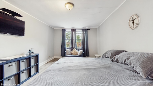 bedroom with light wood finished floors, baseboards, and crown molding