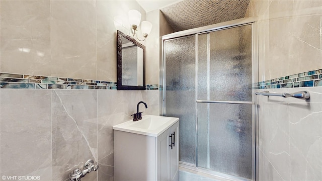full bathroom with tile walls, a shower stall, and vanity