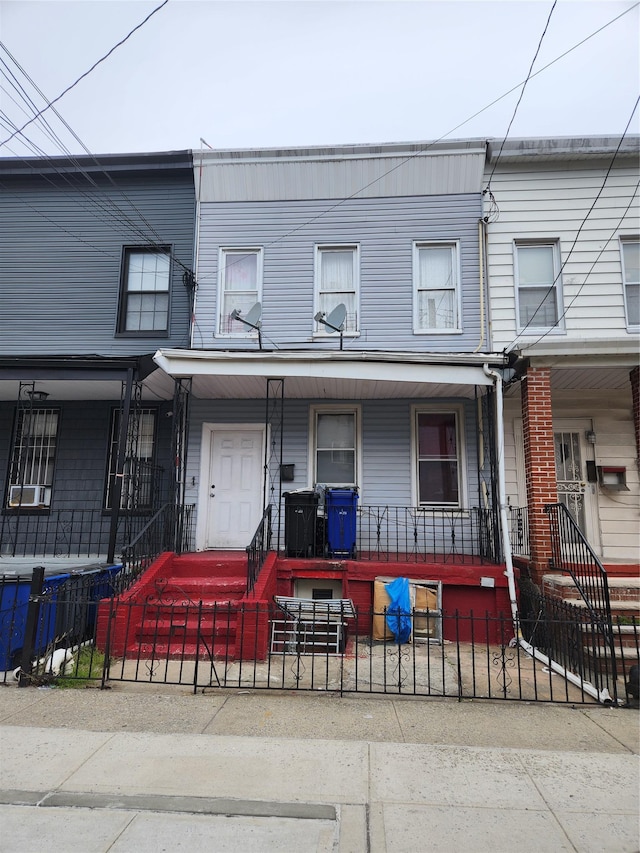 townhome / multi-family property featuring a porch and a fenced front yard