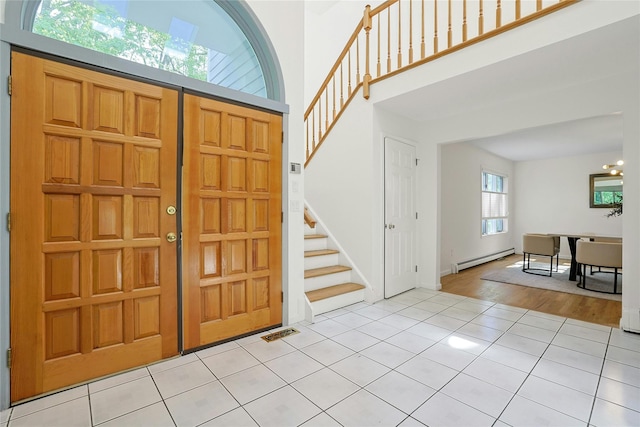 14 Cross Rd, Cortlandt Manor, NY 10567 - entryway with baseboard heating, stairs, light tile patterned floors, a high ceiling, and a chandelier