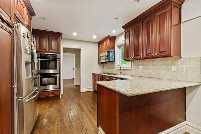 96 Warren St, Somers, NY 10589 - kitchen with stainless steel appliances, a peninsula, dark wood finished floors, a sink, and tasteful backsplash