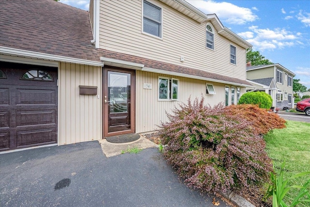 34 Marksman Ln, Levittown, NY 11756 - view of exterior entry featuring roof with shingles and a garage