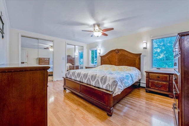 34 Marksman Ln, Levittown, NY 11756 - bedroom with light wood-style flooring, two closets, a baseboard heating unit, and ceiling fan