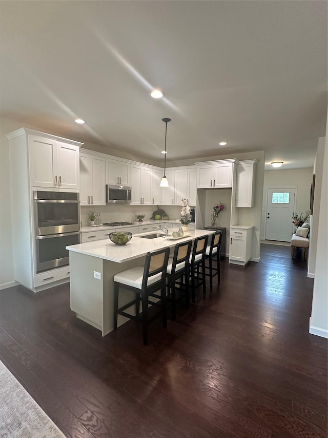 39 Hackensack Heights Rd, Wappingers Falls, NY 12590 - kitchen featuring appliances with stainless steel finishes, dark wood finished floors, recessed lighting, an island with sink, and white cabinetry