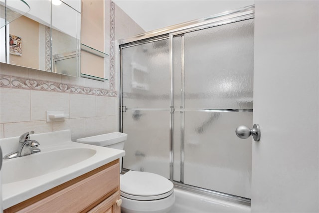 bathroom with toilet, tile walls, vanity, and decorative backsplash