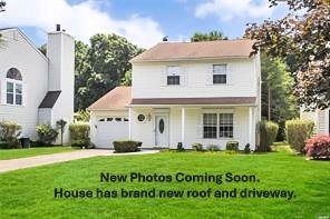 12 Woodchuck Trl, Coram, NY 11727 - traditional home with an attached garage, a front yard, and concrete driveway