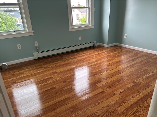spare room featuring a baseboard radiator, wood finished floors, and baseboards