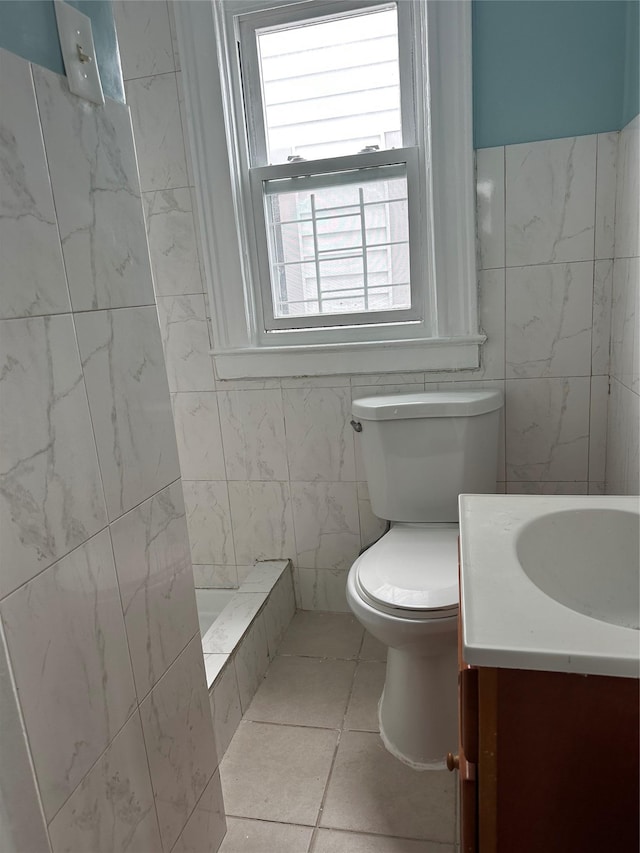 bathroom featuring vanity, toilet, tile walls, a tile shower, and tile patterned flooring