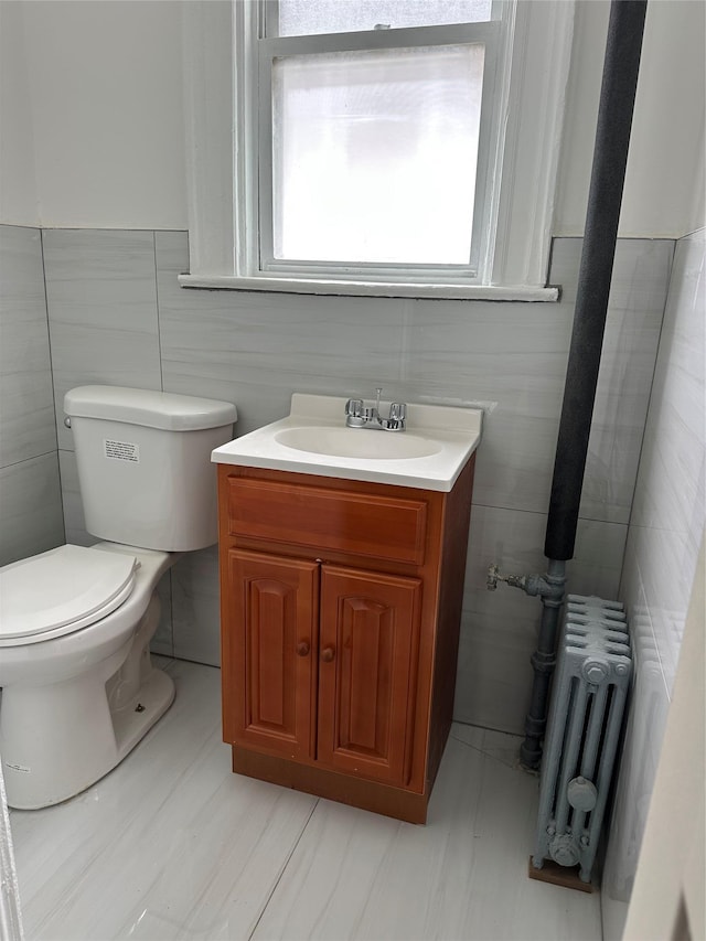 bathroom featuring radiator, tile walls, toilet, and vanity