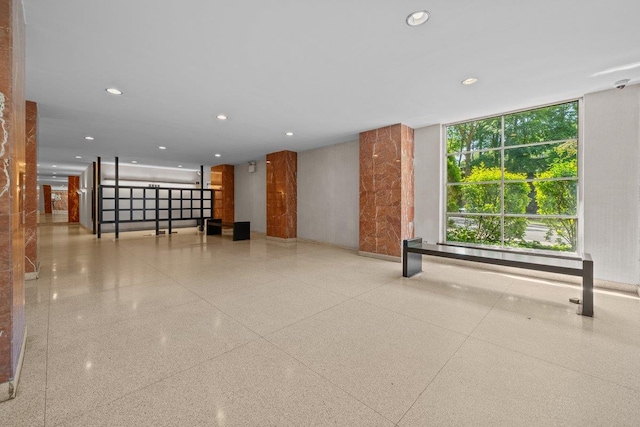 unfurnished living room with speckled floor, recessed lighting, and a wall of windows