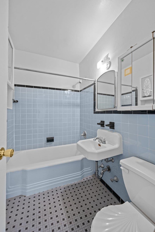 full bathroom with toilet, shower / washtub combination, and tile walls