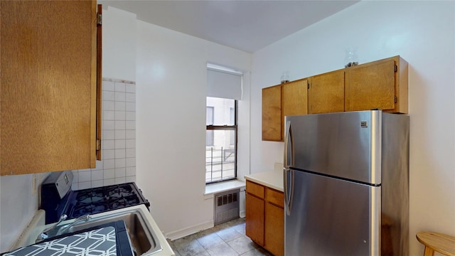 206 W 121st St Unit C, New York Manhattan, NY 10027 - kitchen featuring stainless steel appliances, radiator, brown cabinets, light countertops, and light tile patterned flooring