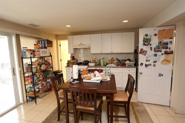4 Rosemont Dr, New City, NY 10956 - kitchen with under cabinet range hood, light tile patterned floors, backsplash, white cabinets, and white appliances