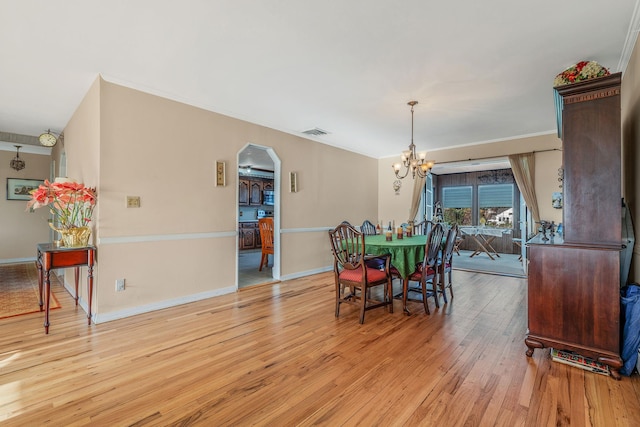 146 Awixa Ave, Bay Shore, NY 11706 - dining room with arched walkways, a chandelier, light wood-style floors, baseboards, and ornamental molding