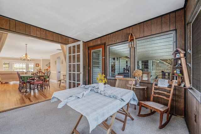 146 Awixa Ave, Bay Shore, NY 11706 - carpeted dining room with wood walls, a chandelier, and wood finished floors